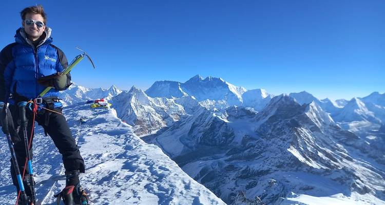 Een klimmer met uitrusting op een met sneeuw bedekte bergkam.