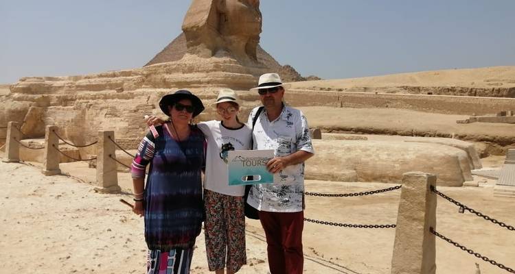 Drei Personen posieren mit einem Schild vor der Sphinx.