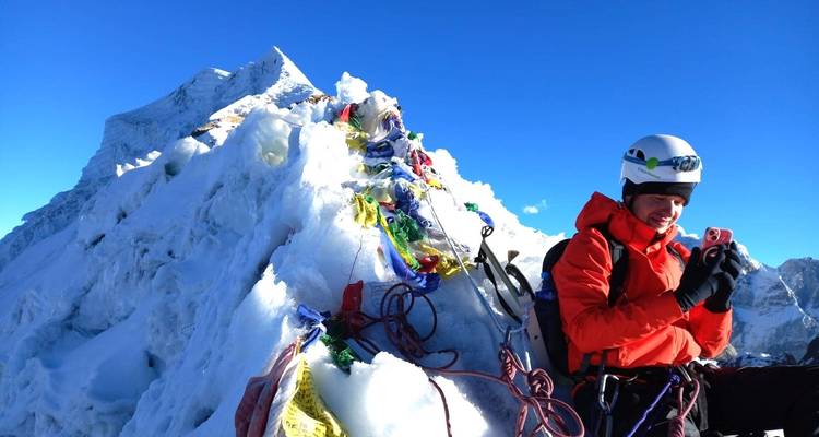 Persoon met klimuitrusting op een besneeuwde bergtop