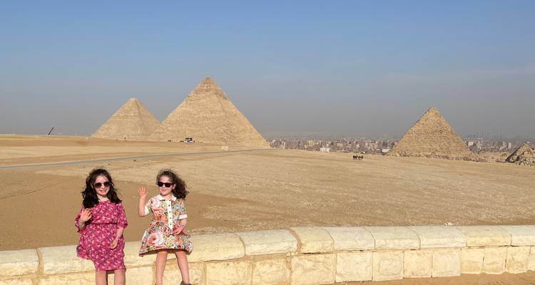 Two children sitting with pyramids in the background