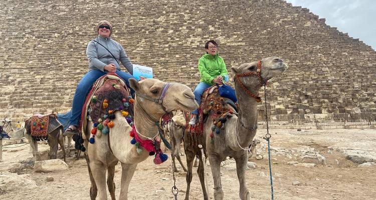 Twee mensen die op kamelen rijden in de buurt van de Grote Piramide.