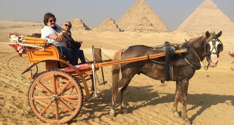 Twee mensen die in een door paarden getrokken koets zitten in de buurt van de Piramides.