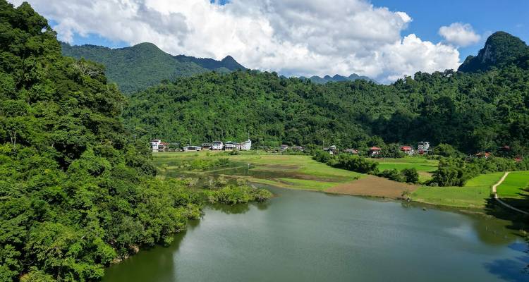 Extensas colinas verdes y bosque rodean un lago tranquilo con un pequeño pueblo en su orilla.