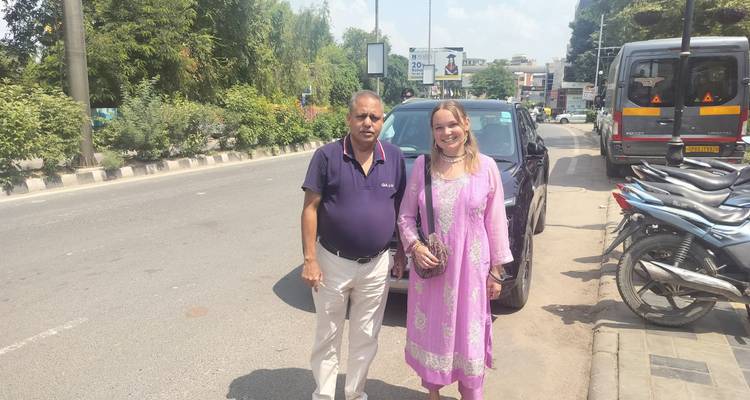 A visitor and their driver stand beside a parked car on a bustling city street
