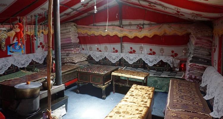 Intérieur d'une tente colorée et décorée avec des sièges et divers textiles.