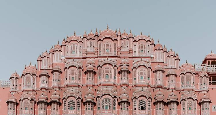 Een gedetailleerd zicht op een roze, gebogen gevel versierd met talrijke ramen.
