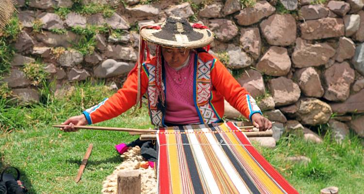 Mujer indígena peruana con ropa colorida tejiendo a mano textiles intrincados en un telar tradicional.