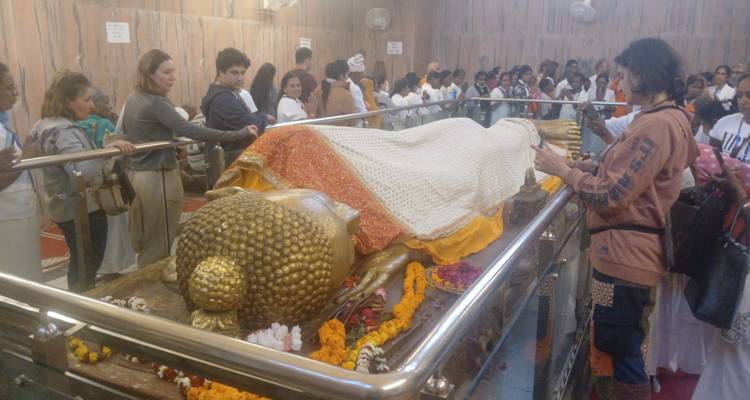 Menschen um eine liegende Buddha-Statue.