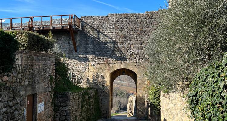 Stenen boogdoorgang door een middeleeuwse muur op een zonnige dag.