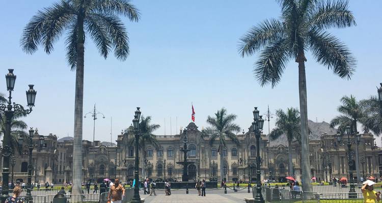 Central square in Lima with palm trees and historic buildings.