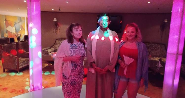 Drie mensen die binnenshuis poseren met kleurrijke lichten en meubilair.