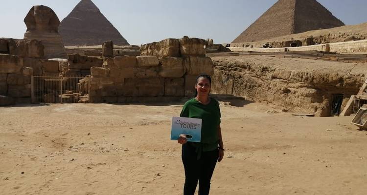 Persoon die poseert voor de piramides van Gizeh met een toeristenbord in de hand.