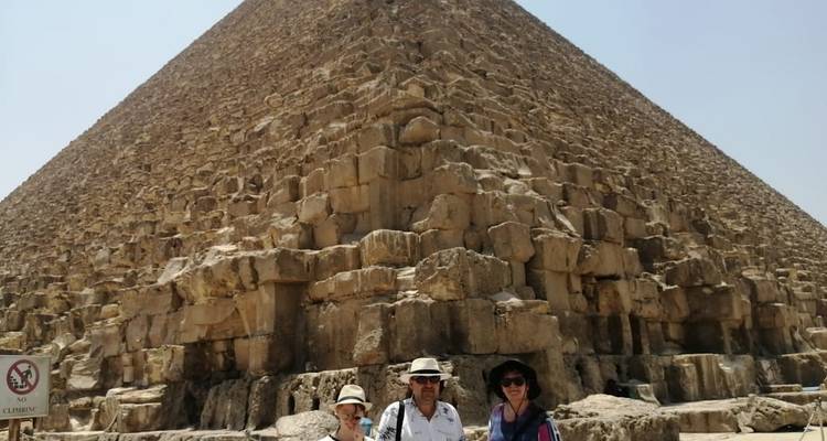 Groep toeristen die aan de voet van een grote piramide staat.