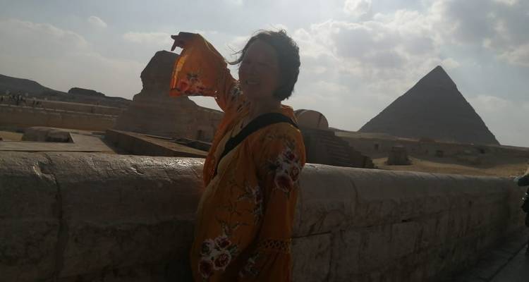 Persoon die wijst naar de Sfinx met een piramide op de achtergrond.