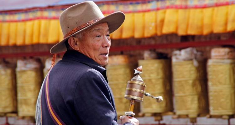 Hombre sosteniendo una rueda de oración cerca de ruedas de oración.