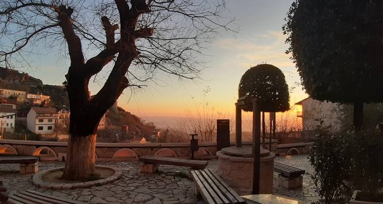 A serene courtyard with benches and a view of a distant horizon at sunset.