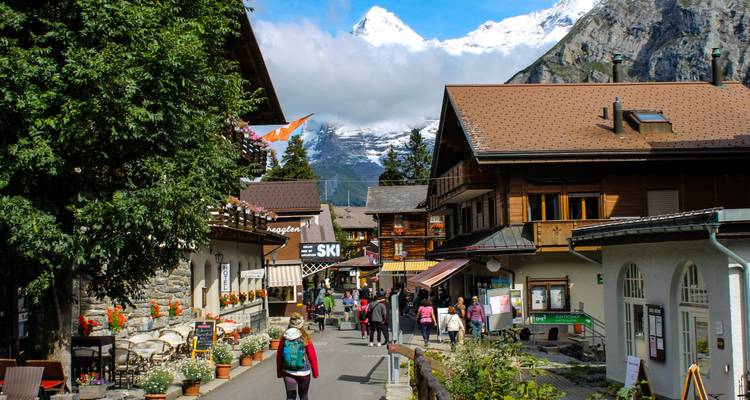 Encantadora calle alpina bordeada de chalets y flores coloridas bajo picos nevados