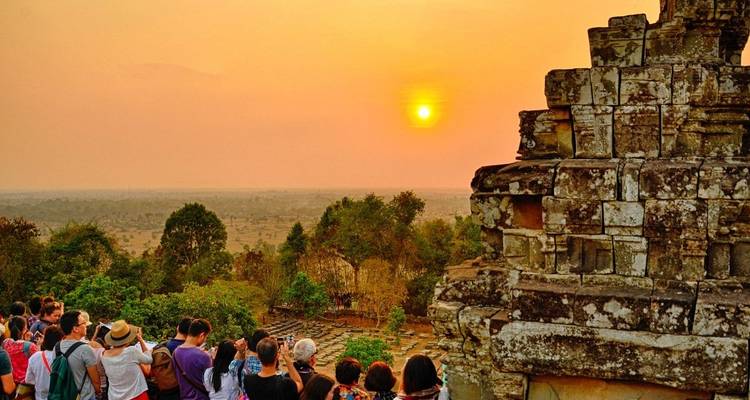 A sunset view from a temple overlooking the landscape with multiple people watching.