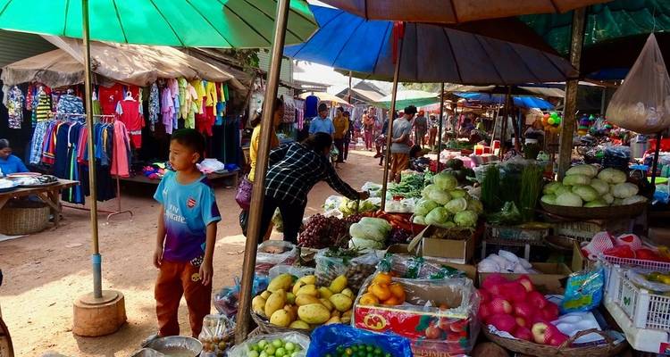 A bustling local market with various fruits and vegetables on display.