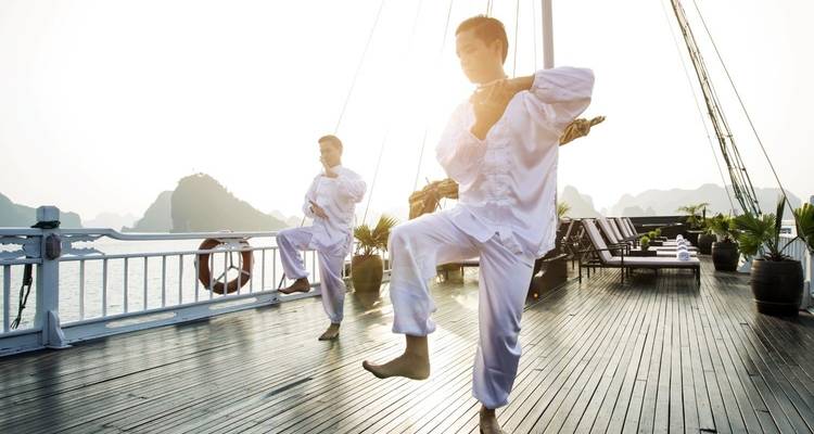 Zwei Personen praktizieren Tai Chi auf einem Kreuzfahrtdeck mit Aussicht.