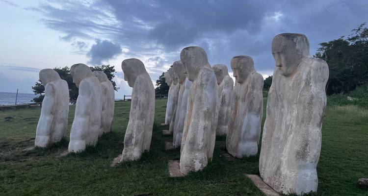 Row of weathered statues at a historical site by the sea.