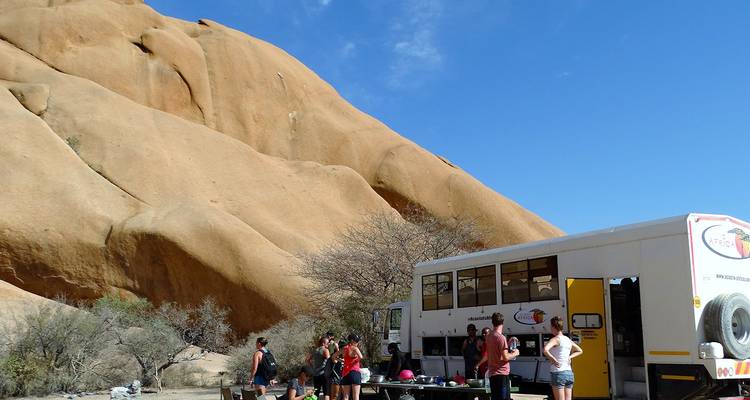 Groupe de personnes près d'un camion de safari sur un site rocheux.