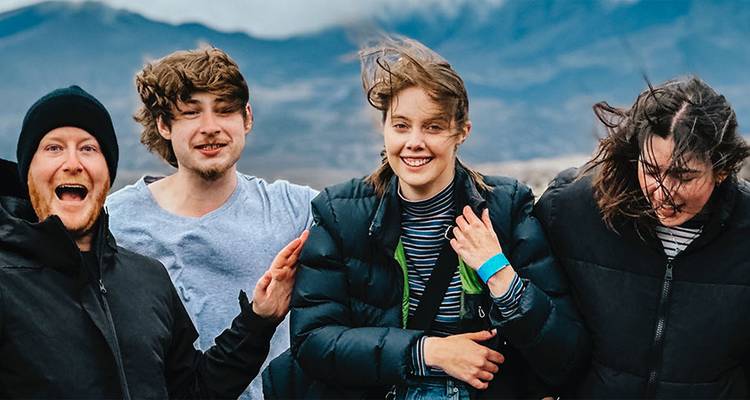Groupe de quatre personnes souriantes avec un paysage montagneux.