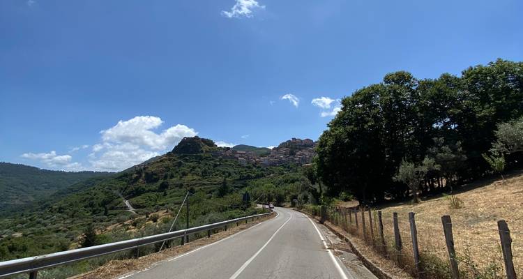 Uitzicht vanaf een weg met heuvels en dorp in de verte.