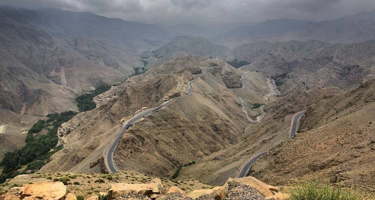 Vue panoramique d'une route sinueuse traversant un paysage montagneux aride.
