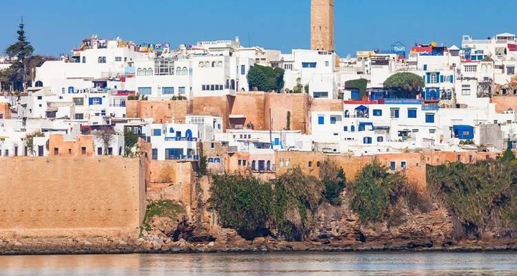Weiße Stadtgebäude an der Küste mit Leuchtturm.