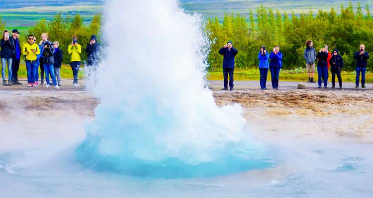 Geyser en éruption avec des gens qui prennent des photos.