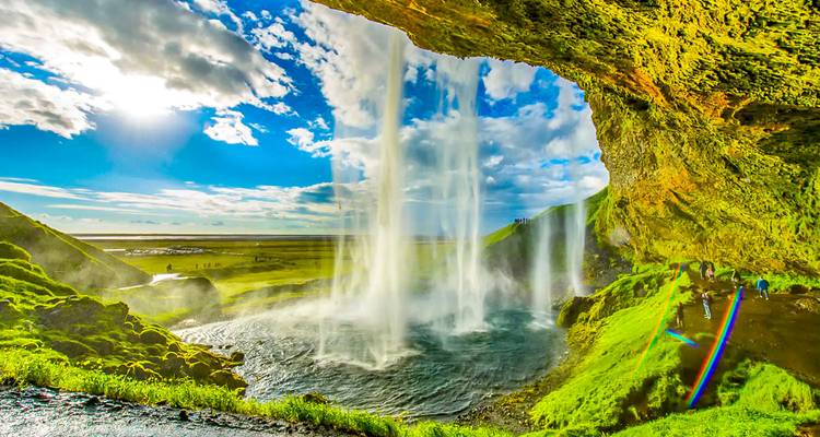 Cascade vue de derrière avec une végétation luxuriante et du soleil.