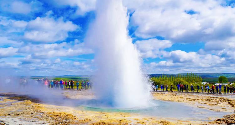 Un geyser en éruption avec des spectateurs autour.
