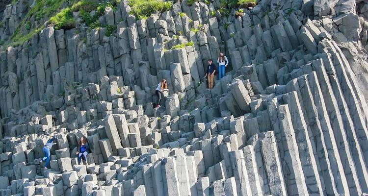 Des gens escaladant des colonnes de basalte sur une falaise.