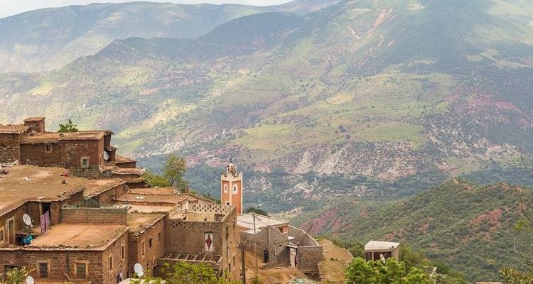 Bergdorf mit einer Moschee und grünen Hügeln.