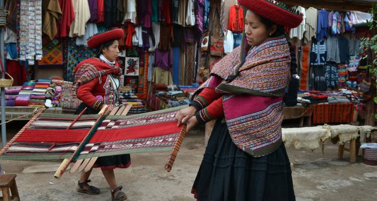Des femmes en vêtements traditionnels tissent dans une zone de marché.