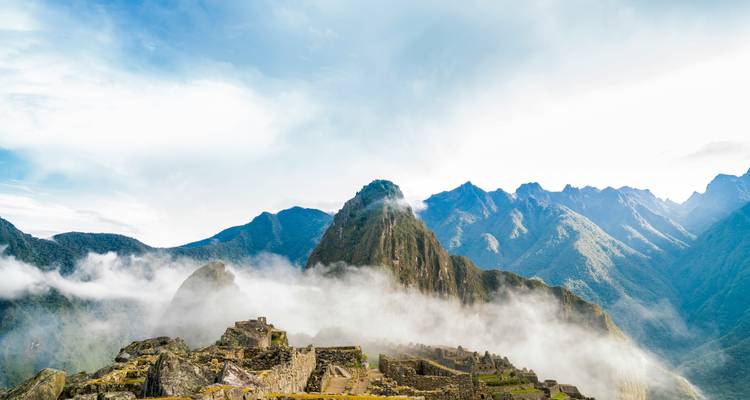 Machu Picchu avec des nuages et les pics environnants.