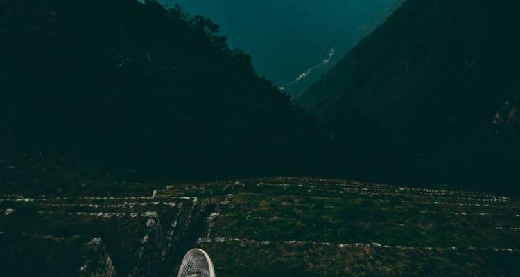 Uitzicht over een steil dalpad met een zichtbare schoen.