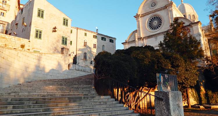 Steinerne Stufen, die zur weißen Kathedrale von Šibenik führen, die in warmem, goldenem Licht erstrahlt