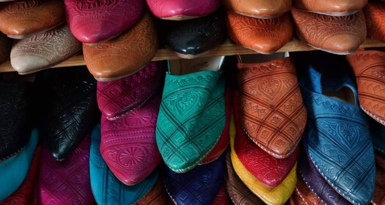 Une rangée colorée de babouches marocaines traditionnelles en cuir soigneusement empilées en vitrine.