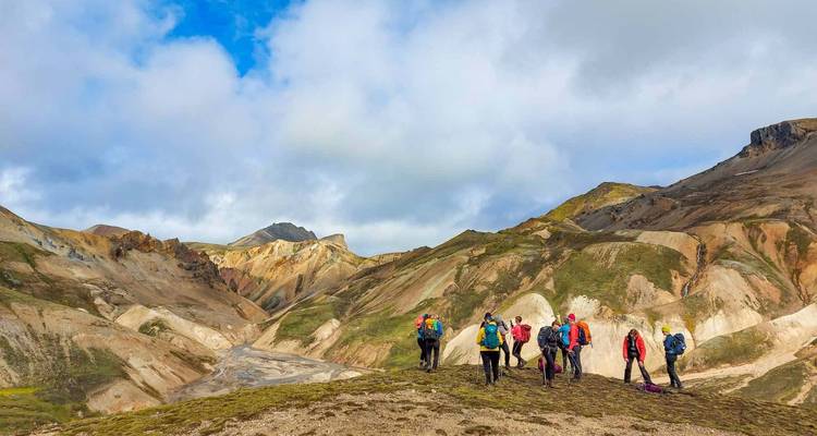 Wandelaars die op een kleurrijke rioliet bergrug staan en uitkijken over de vallei van Landmannalaugar.