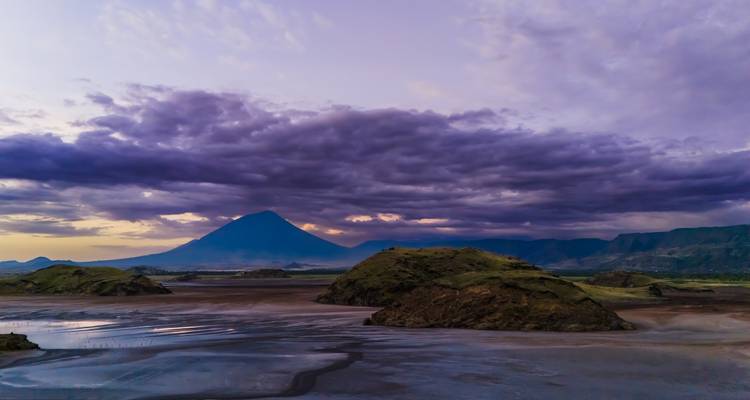 Dramatische Landschaft mit Bergen unter einem farbenfrohen Himmel.