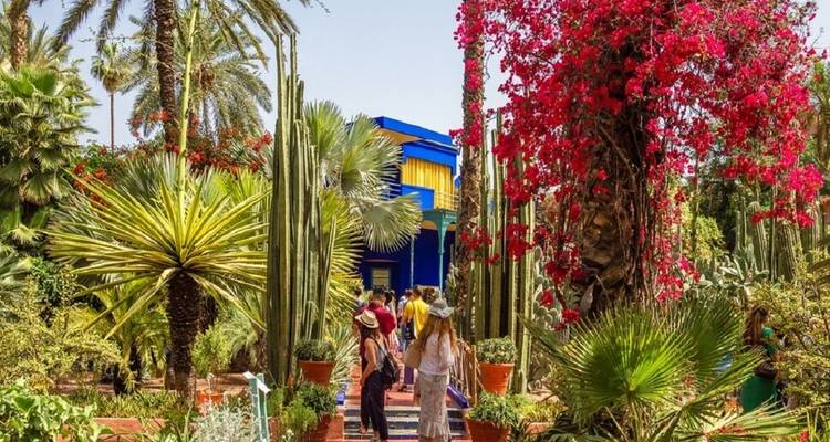 Jardin à Marrakech avec des plantes exotiques et des gens qui se promènent.