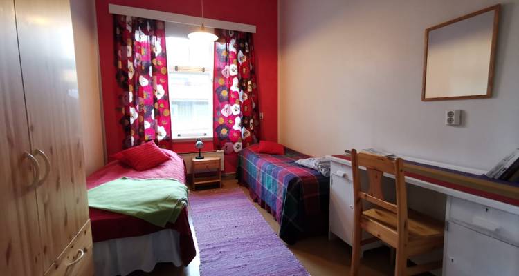 Einfaches Gemeinschaftszimmer mit Betten und minimaler Dekoration.