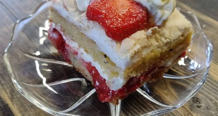 Ein Stück geschichteter Erdbeerkuchen auf einem Glasteller.