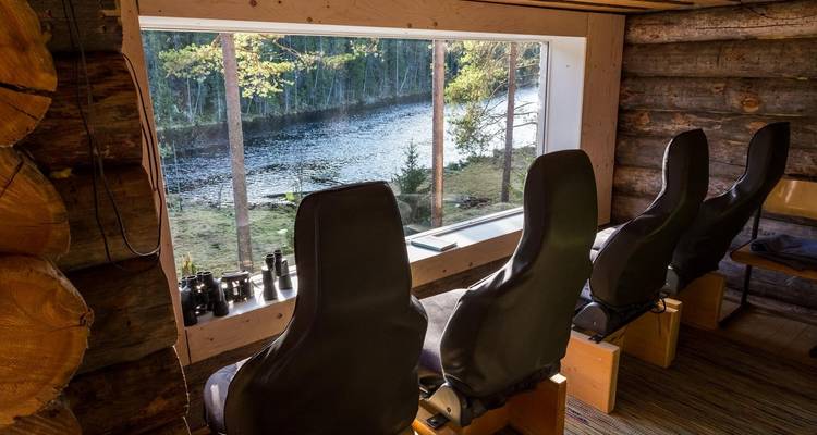 Intérieur d'une cabine d'observation avec des sièges donnant sur une rivière.
