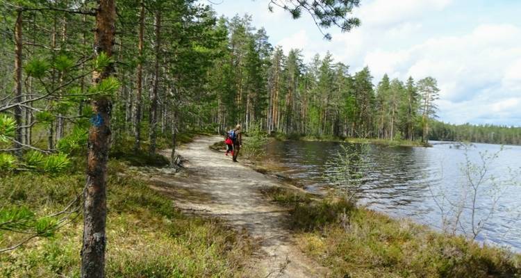 Couple se promenant le long d'un sentier au bord d'un lac dans une forêt.