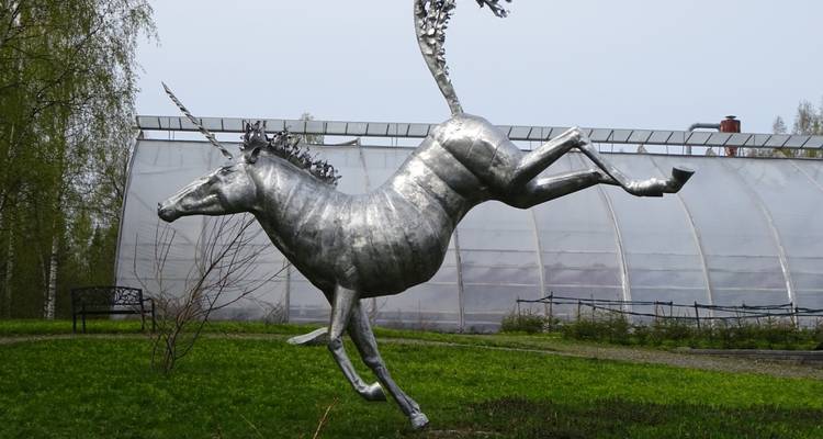 A metallic unicorn statue in a garden setting.