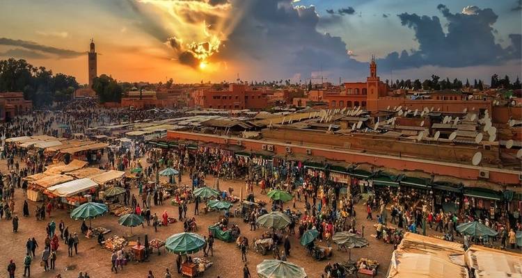Place de marché animée à Marrakech avec ciel de coucher de soleil.