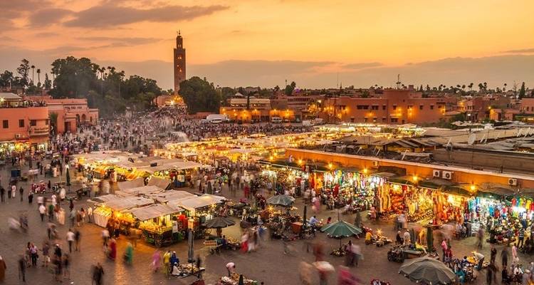 Place de marché animée avec des étals et la mosquée Koutoubia à Marrakech.